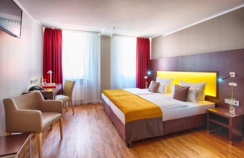 ein Hotelzimmer mit einem großen Bett und einem Stuhl in der Unterkunft Leonardo Hotel München City Center in München