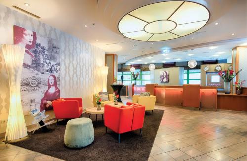 a lobby with red chairs and a waiting room at Leonardo Hotel Mannheim City Center in Mannheim