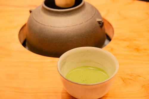 een kopje groene vloeistof op een houten tafel bij Matsumoto Tourist Hotel in Matsumoto