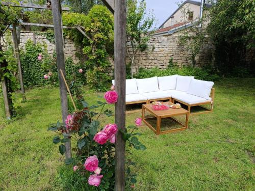 un canapé blanc dans un jardin avec des roses roses roses dans l'établissement Gite "Chez Eléonore et Axel", à Gouvieux