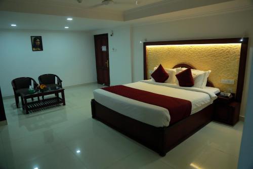 um quarto de hotel com uma cama grande e uma cadeira em Hotel Savera Park em Thrissur