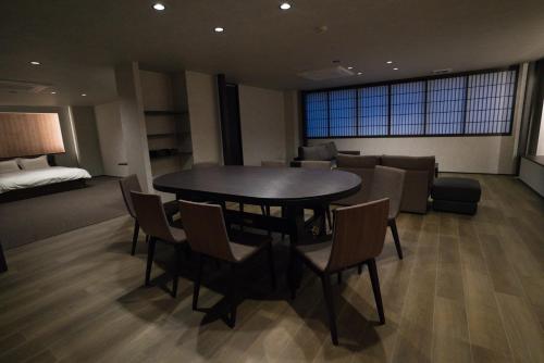 金沢市にあるMusashi Condo Kanazawaのテーブル、椅子、ソファが備わる客室です。