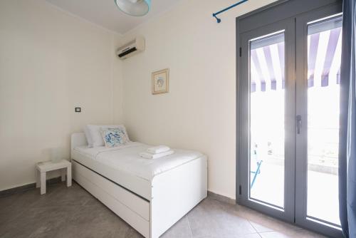 um quarto branco com uma cama e uma porta de vidro deslizante em Sempre il Mare em Pireu