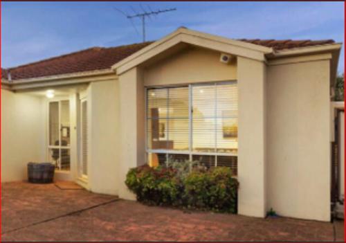 a white house with a large window at A Unique Holiday Home between Avalon Airport and Melbourne CBD in Werribee