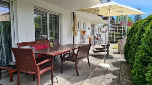 a wooden table and chairs with an umbrella on a patio at 'Tor zum Schwarzwald' Ferienwohnungen in Wildberg