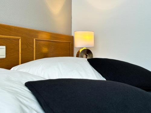 - une chambre avec un lit blanc et une tête de lit en bois dans l'établissement Hotel DenRiKo, à Heidelberg