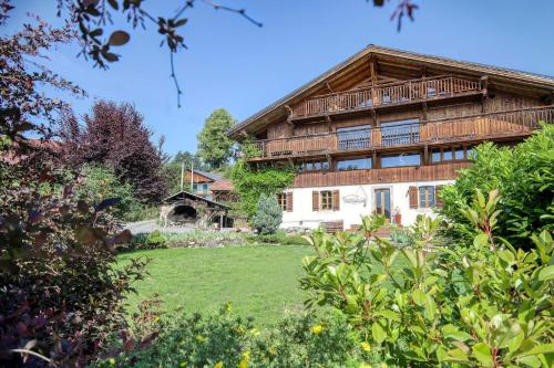 een groot houten huis met een gazon ervoor bij Ferme du Ciel in Samoëns