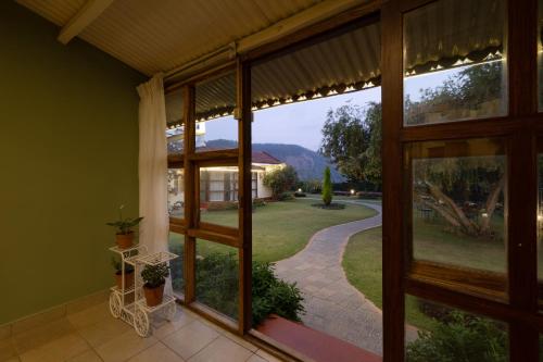 een kamer met een groot raam met uitzicht op een tuin bij Sherlock in Ooty