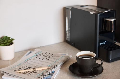 eine Tasse Kaffee auf einem Tisch neben einer Zeitung in der Unterkunft Kennigo Hotel Brisbane, Independent Collection by EVT in Brisbane