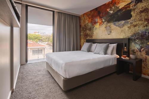 ein Schlafzimmer mit einem großen Bett und einem großen Fenster in der Unterkunft Kennigo Hotel Brisbane, Independent Collection by EVT in Brisbane