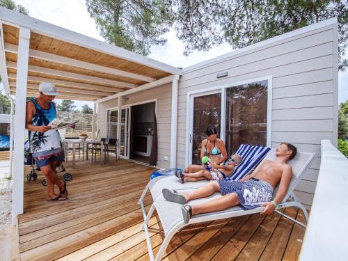 a group of people sitting on the porch of a house at Mobile homes in Zaton Holiday Resort, with large pool area in Zaton