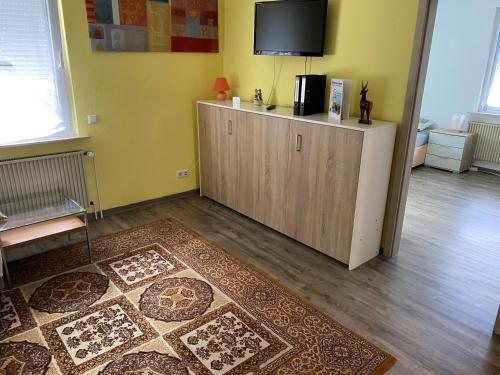 - un salon avec une télévision au-dessus d'une armoire dans l'établissement Ferienwohnung Pfeifer, à Friedrichsdorf