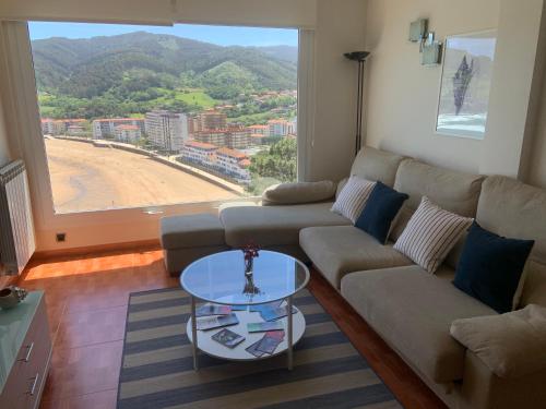 sala de estar con sofá y mesa de cristal en El BALCON DE BAKIO, en Bakio