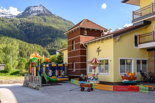 un bâtiment avec une aire de jeux en face d'une maison dans l'établissement Hotel der Wolkensteinbär, à Bramberg am Wildkogel