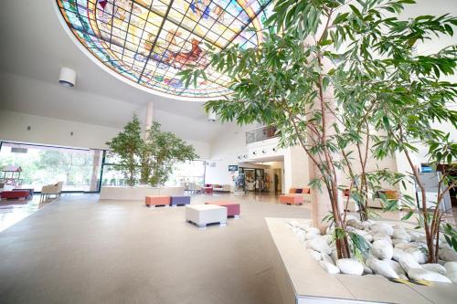 un grand hall avec un plafond en vitraux et des arbres dans l'établissement Ohtels Vil·la Romana, à Salou