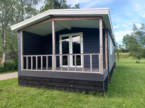 een klein huis met een veranda op het gras bij IJsvogel in Schipborg