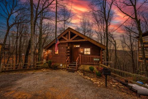 een blokhut in het bos met een Amerikaanse vlag bij Log Cabin, Hot Tub, Fireplace, Pool Table & Views! in Sevierville