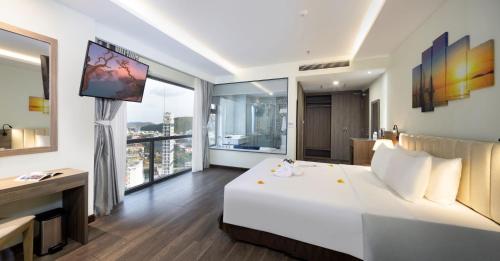 1 dormitorio con 1 cama blanca grande y ventanas grandes en Xavia Hotel, en Nha Trang