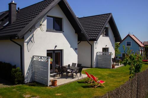 een wit huis met een tafel en stoelen in de tuin bij Domki u Marty - Władysławowo in Władysławowo