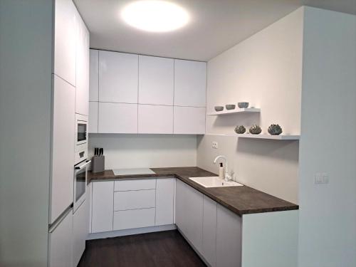 a white kitchen with white cabinets and a sink at Tabáň Marble apartment (city center & free parking) in Nitra