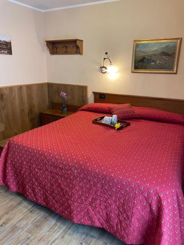 a bedroom with a bed with a red bedspread at Hotel Le Petit Abri in Champoluc