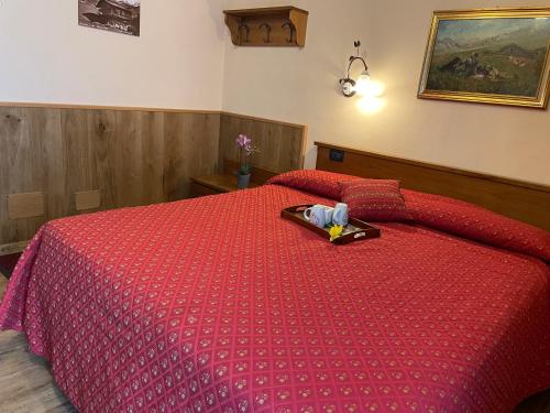 a bedroom with a red bed with a tray on it at Hotel Le Petit Abri in Champoluc