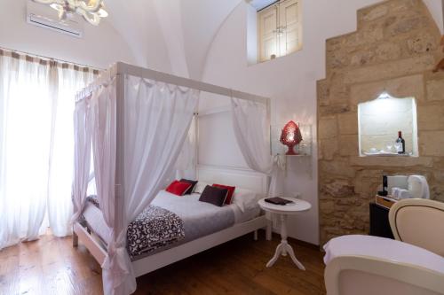 una camera con letto a baldacchino e cuscini rossi di Le Nicchie luxury rooms a Lecce