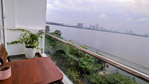 einen Balkon mit einem Tisch und Blick auf das Wasser in der Unterkunft Hanoi Home 2 - Lake View Apartment in Hanoi