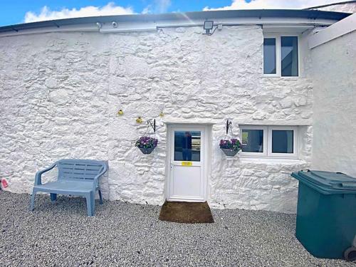 un bâtiment blanc avec un banc bleu devant lui dans l'établissement Bumblebee Cottage, à Redruth