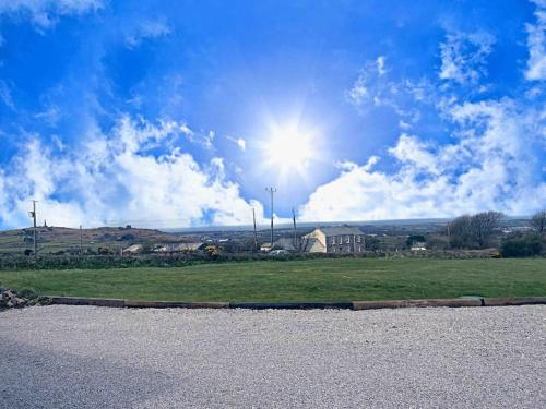 un soleil dans le ciel sur un champ vert dans l'établissement Bumblebee Cottage, à Redruth