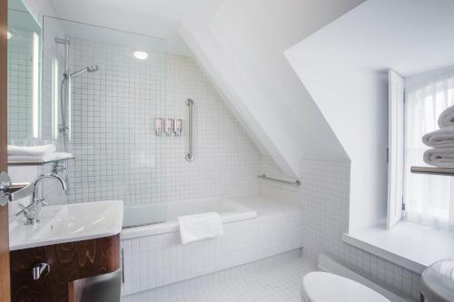 Baño blanco con bañera y lavamanos en Monastère des Augustines, en Quebec