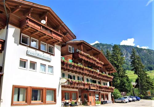 um hotel nas montanhas com carros estacionados em Hotel Rododendro Val di Fassa em Campitello di Fassa