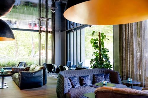 a living room with a couch and chairs and windows at Motel One München - Deutsches Museum in Munich