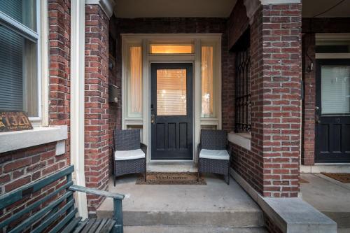 uma porta da frente de uma casa de tijolos com duas cadeiras em Charming New Orleans-Style Apartment with Gated Courtyard! em Little Rock