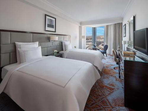 a hotel room with two beds and a television at Swissotel Makkah in Makkah