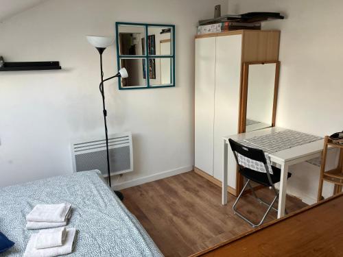 um quarto com uma cama, uma mesa e um espelho em Studio La Belle Vie em Suresnes