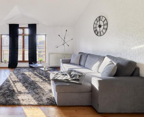 ein Wohnzimmer mit einem Sofa und einer Uhr an der Wand in der Unterkunft Traumferienwohnung Domblick I Parkplatz inklusive I Zentral gelegen I Altstadtnähe I Netflix in Limburg an der Lahn