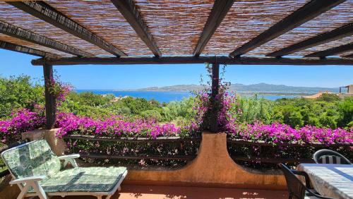 a patio with purple flowers and a view of the water at LA TERRAZZA SUL MARE - panoramic cottage overlooking sea and Caprera island in a quiet residential area - 150 mt from the sea in La Maddalena