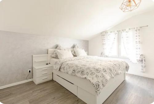 een witte slaapkamer met een wit bed en een raam bij Maisonnette avec terrasse in Straatsburg