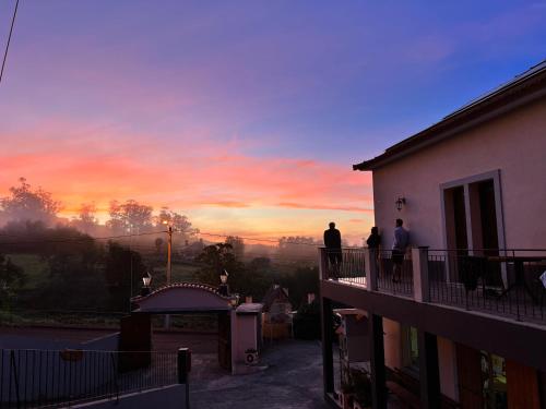 Três pessoas de pé numa varanda a ver o pôr-do-sol. em Casa Os Manos em Santana