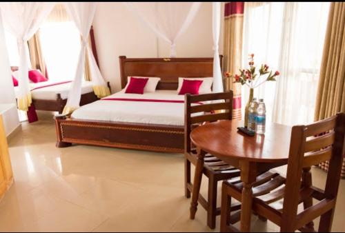 um quarto com uma cama, uma mesa e cadeiras em Sienna Beach and Safaris Hotel em Entebbe