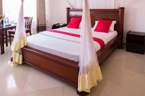 um quarto com uma cama com almofadas vermelhas em Sienna Beach and Safaris Hotel em Entebbe