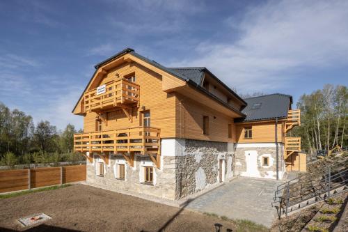 een groot houten huis met een balkon erboven bij Apartmán Oliva in Horní Planá