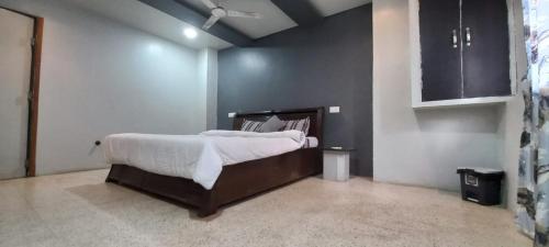 1 dormitorio con 1 cama grande con sábanas blancas en Swanky Sojourns Cosy Home Stay, en Kolhapur