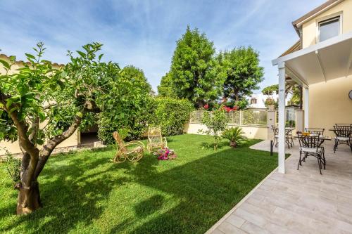 a backyard with a lawn with a tree and chairs at Casa Rita in Sabaudia