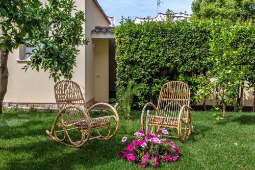 three rattan chairs sitting in a yard with flowers at Casa Rita in Sabaudia