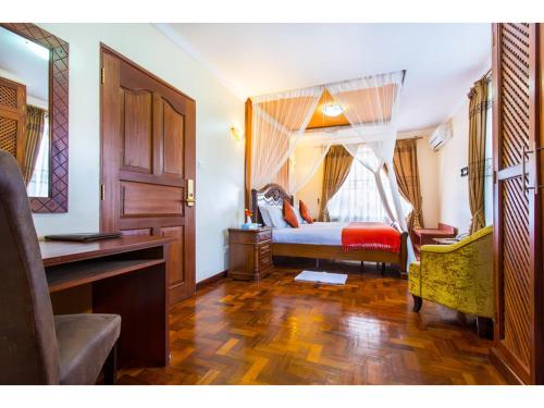 - une chambre avec un lit, un bureau et une fenêtre dans l'établissement Wigot Gardens Hotel, à Kisumu