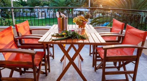 una mesa de madera con sillas y flores en un patio en Villa Nefeli Skiathos, en Skiathos