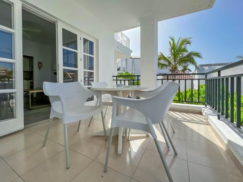 comedor blanco con mesa y sillas en el balcón en Apartamentos Parque del Sol, en Adeje