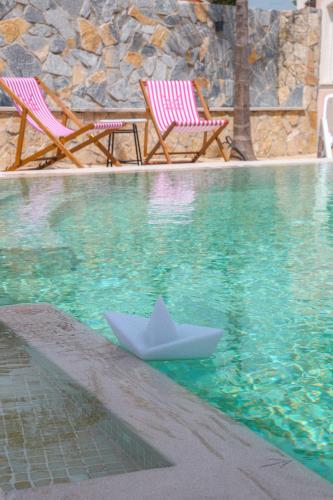 a paper boat in the water next to two chairs at Casa Selimi in Ulcinj